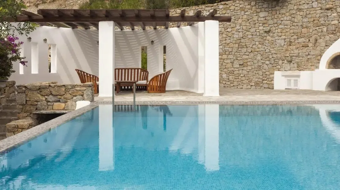 A swimming pool in front of a shaded seating area.