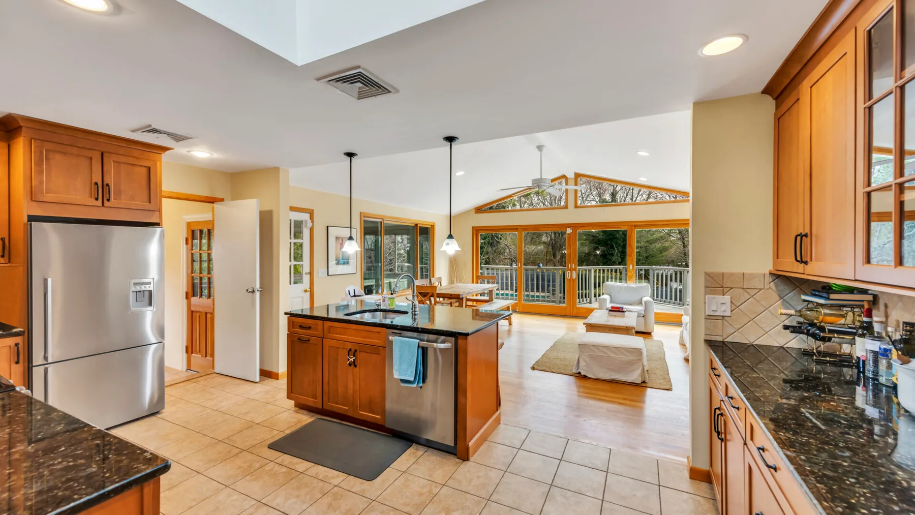 Cocina y sala de estar abiertas, con gabinetes de madera y una isla central.