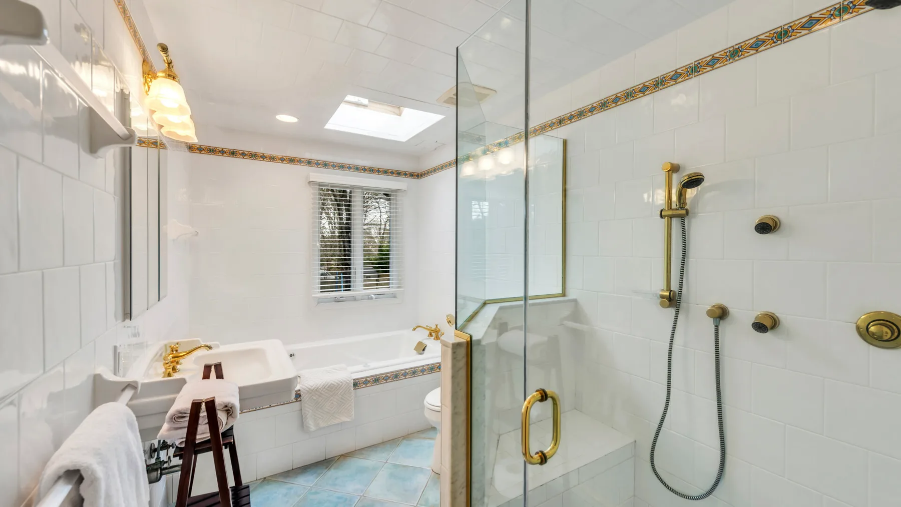 Un baño luminoso con azulejos, bañera y ducha con mampara de vidrio.