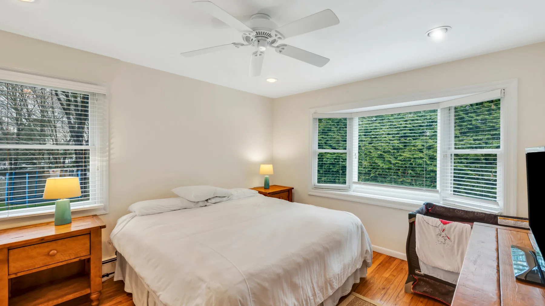 Un dormitorio luminoso con una cama junto a ventanas grandes.