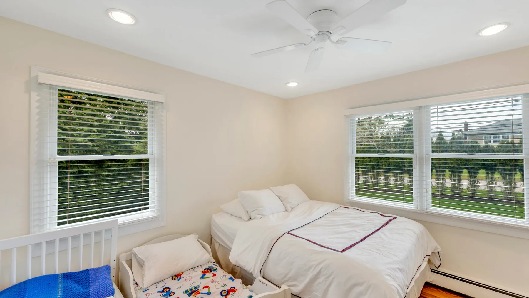 Un dormitorio luminoso con una cama y una pequeña zona de descanso junto a las ventanas.