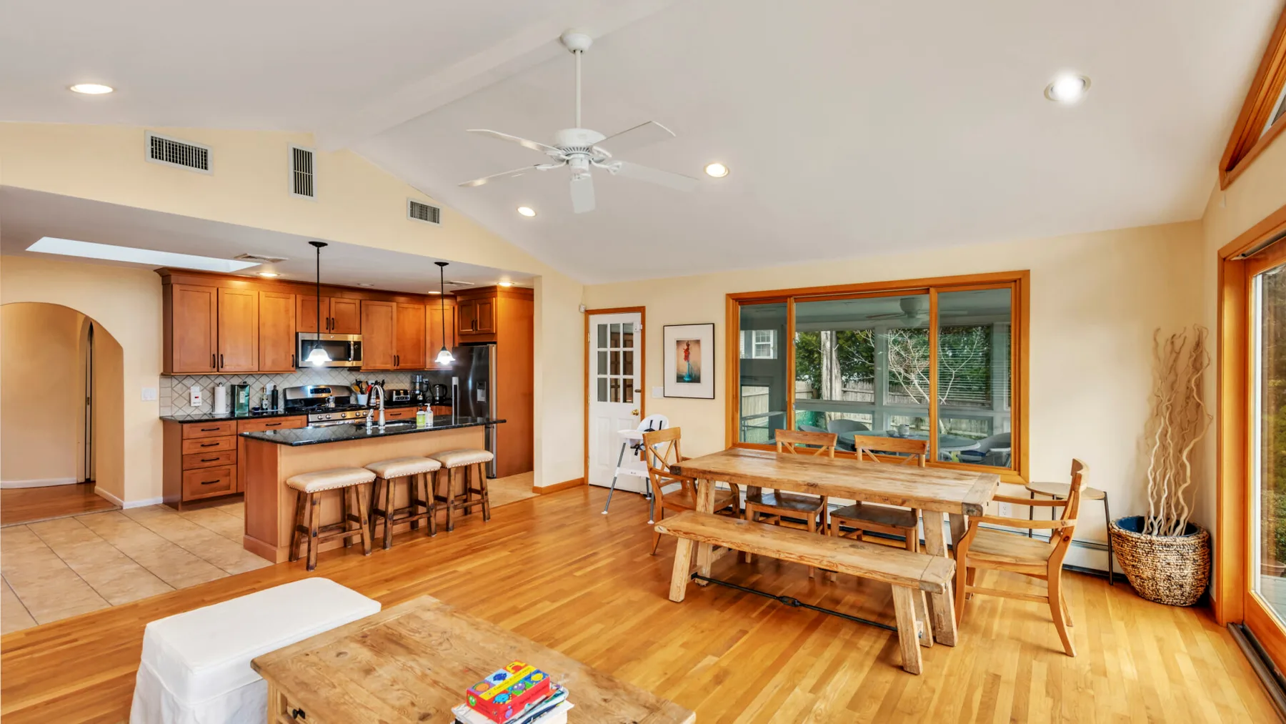 A dining area with a wooden table and seating beside an open kitchen.