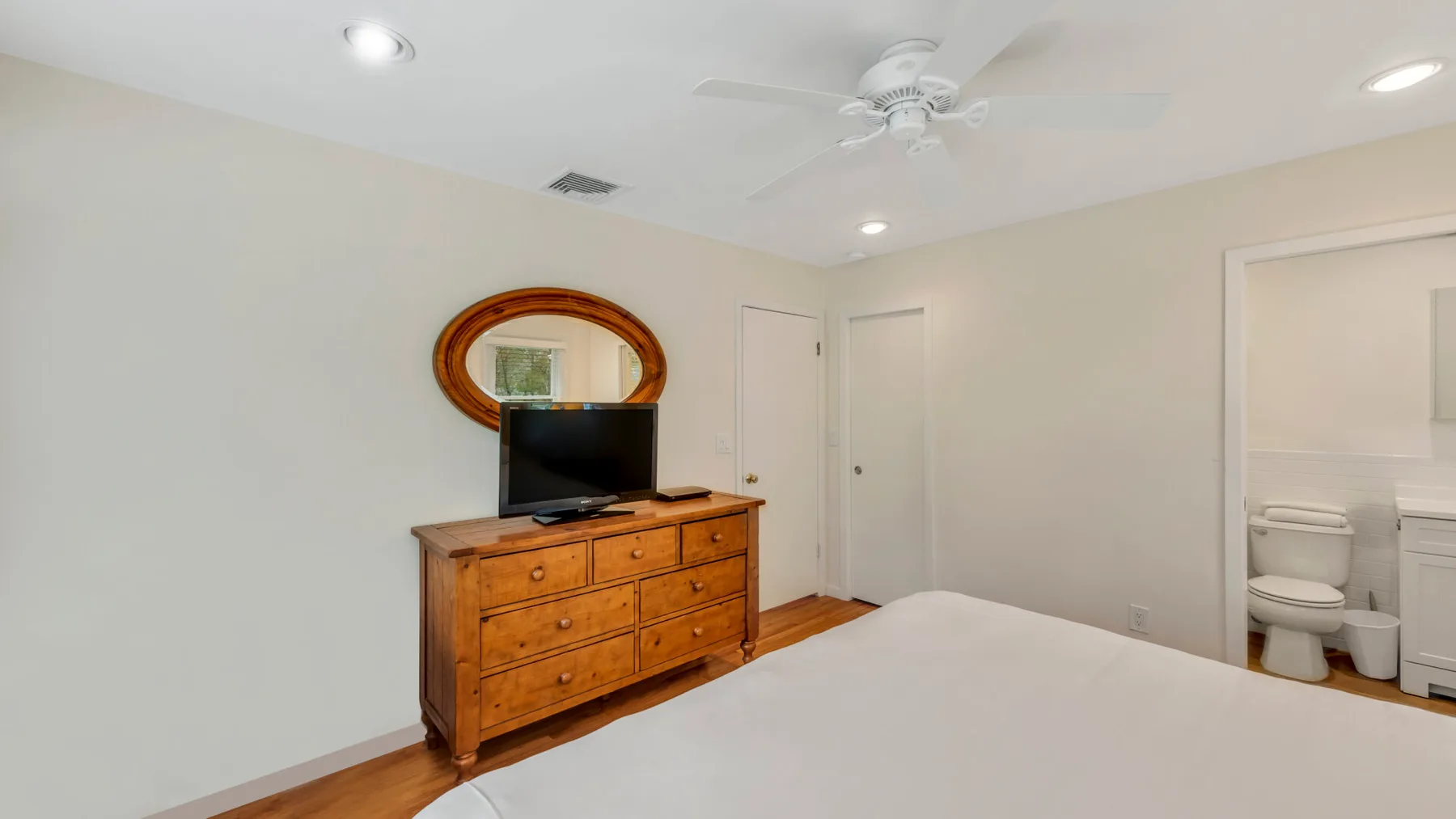 Un dormitorio con una cómoda de madera y un televisor junto a la cama.