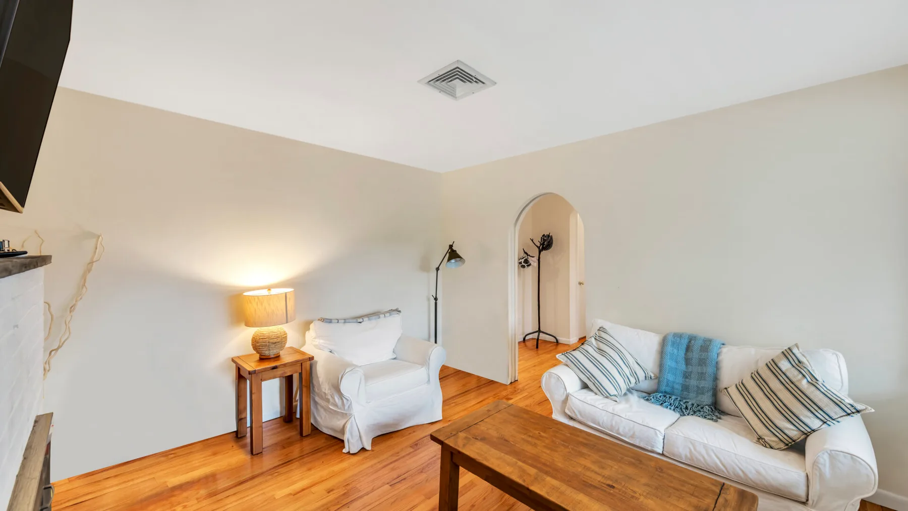 Una sala de estar con un sofá blanco y un sillón junto a una mesa de centro de madera.