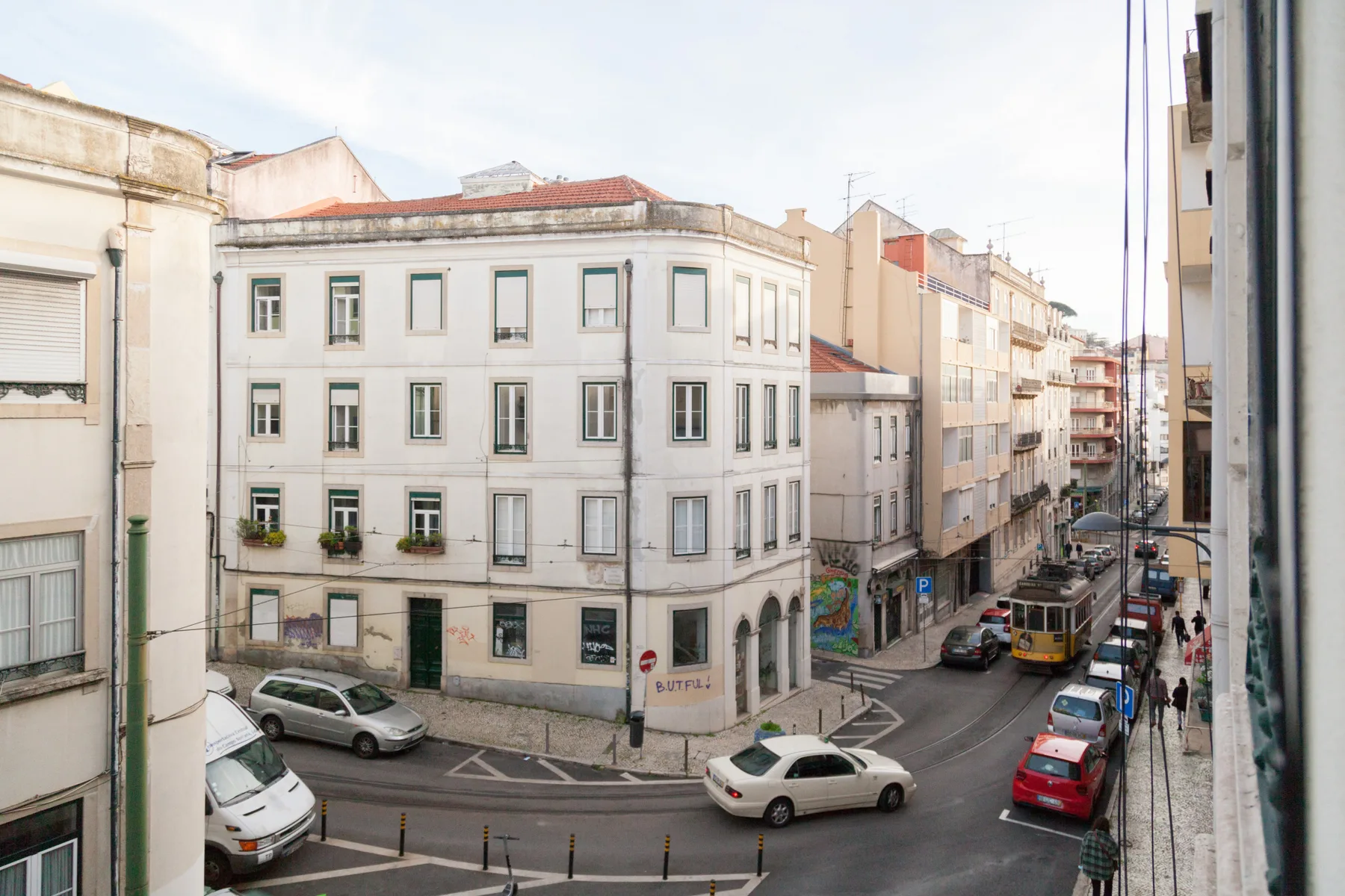 Una calle urbana flanqueada por edificios de varias plantas y coches estacionados.