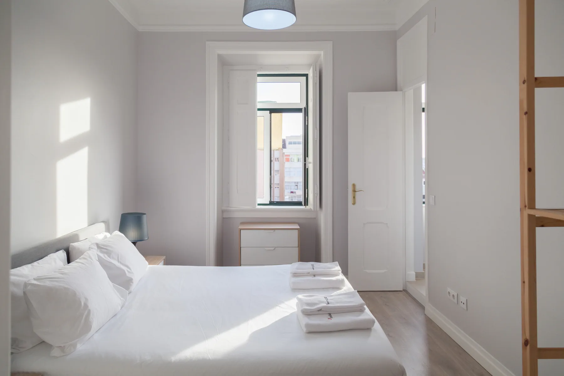 Un dormitorio luminoso con una cama bien hecha y una ventana.