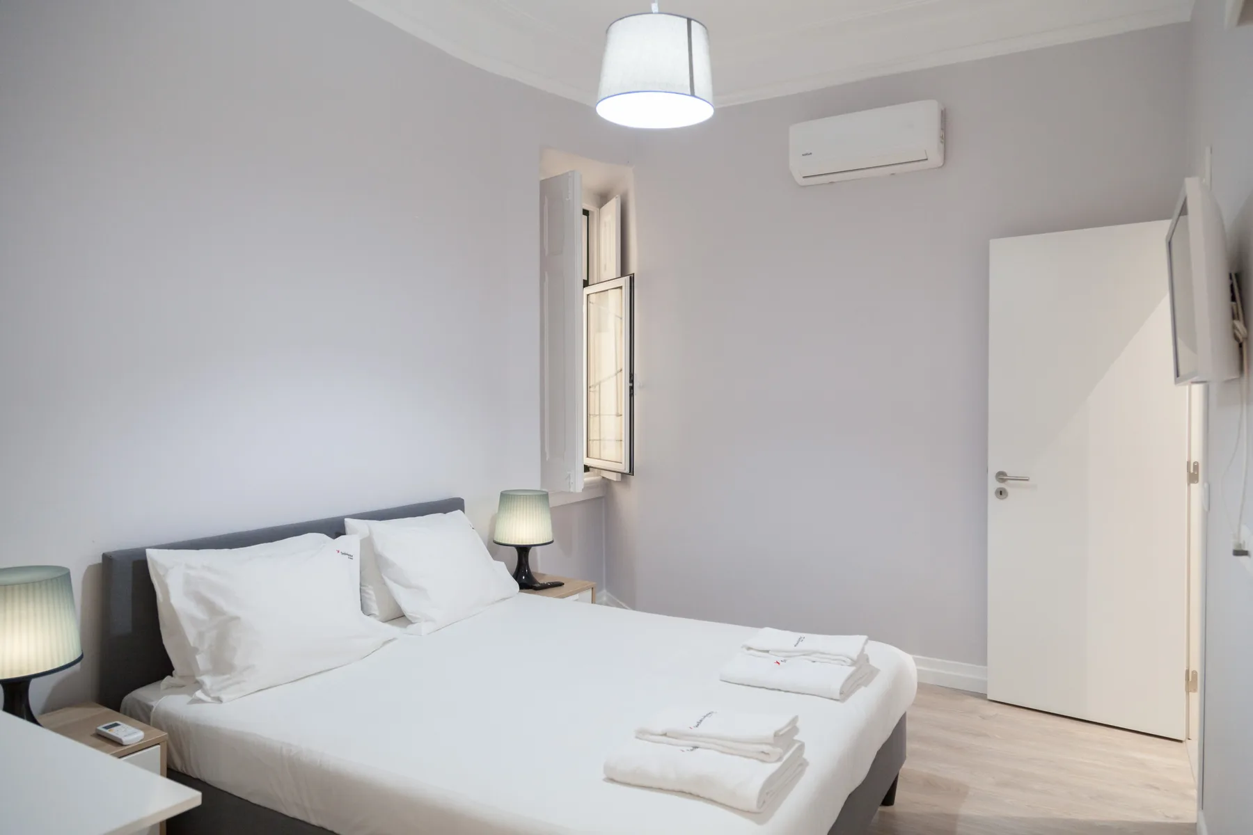 Un dormitorio luminoso con una cama tendida y una ventana.