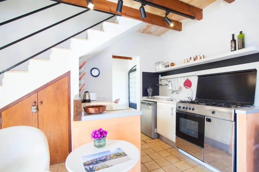 Una cocina compacta está bajo una escalera, con una encimera y electrodomésticos.