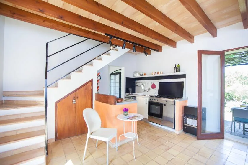 Una cocina y comedor luminosos con vigas de madera vistas y una puerta abierta.