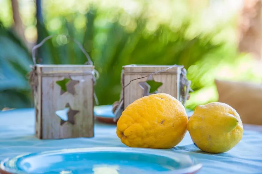 Dos limones están sobre una mesa azul frente a pequeños faroles decorativos.