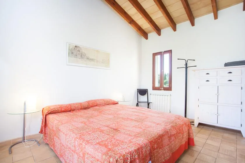Un dormitorio con una cama cubierta con una colcha estampada en tonos coral.