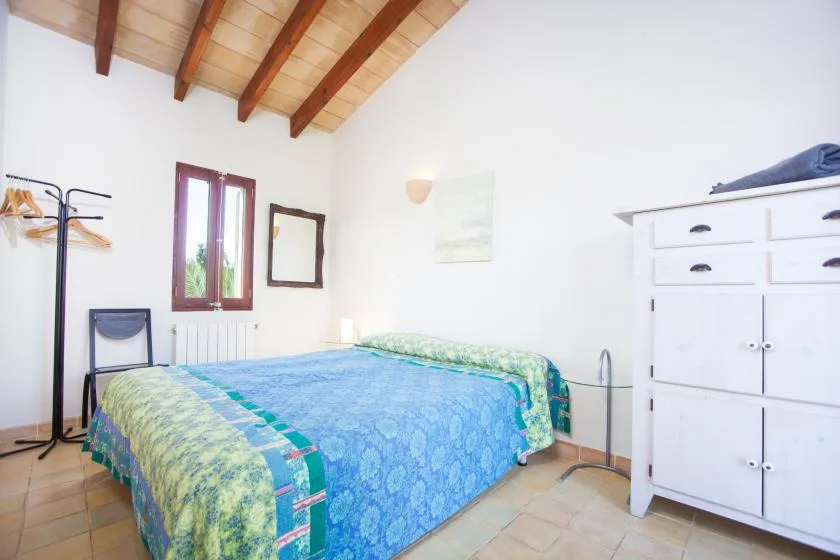 Un dormitorio con una cama cubierta con ropa de cama azul estampada y un armario blanco.