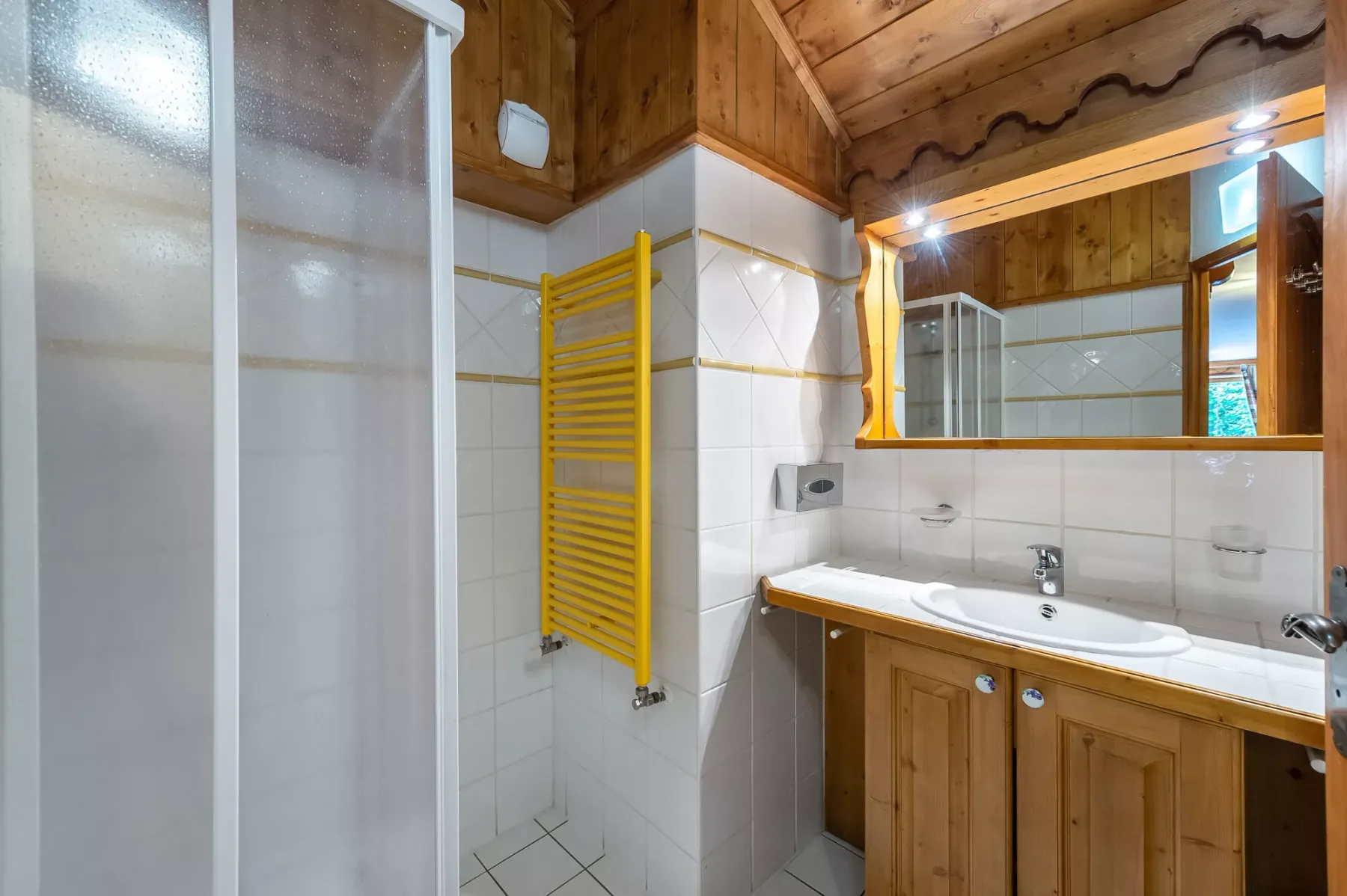 Un baño con ducha, lavabo y mueble de madera.