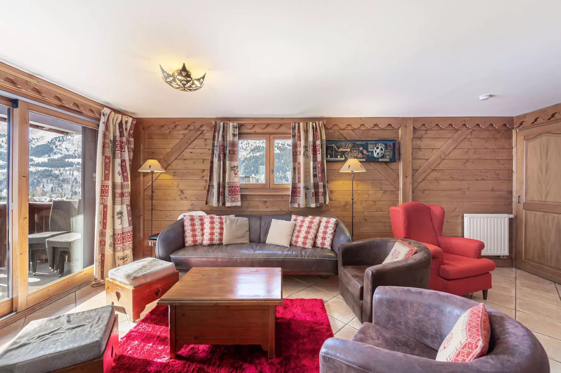 A wood-paneled living room with seating around a coffee table on a red rug.