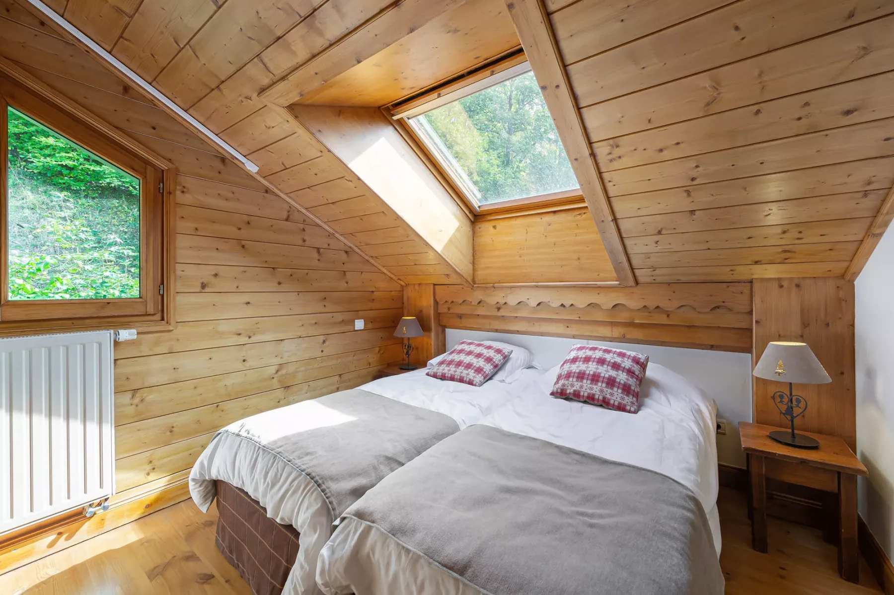 Un dormitorio revestido de madera con dos camas bajo una claraboya.
