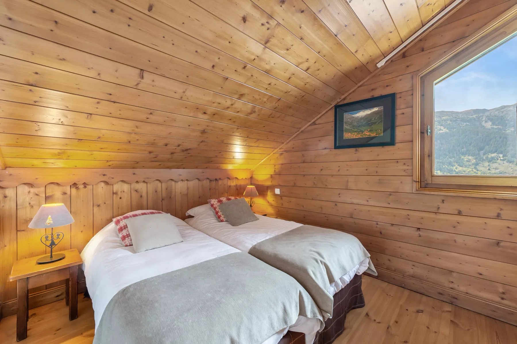 Un dormitorio de madera con dos camas y una ventana con vistas a las montañas.