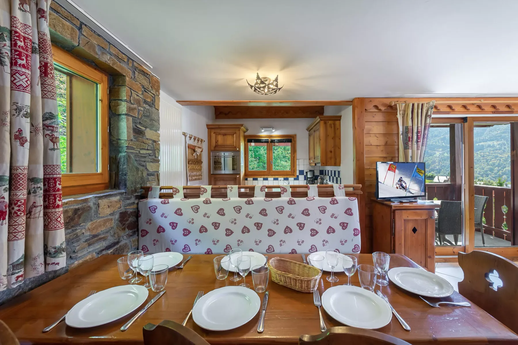 A dining area with a set table and a kitchen in the background.