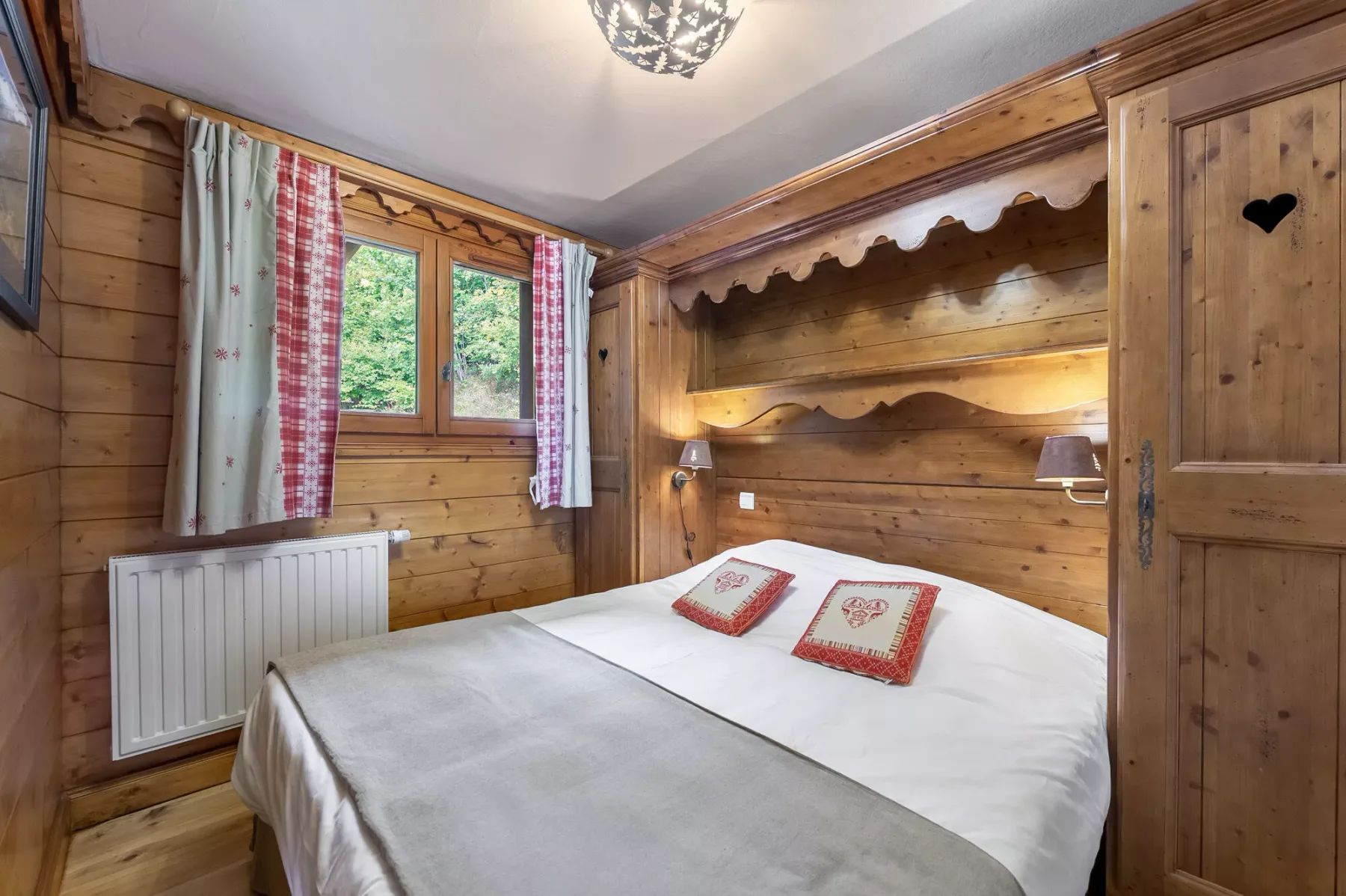 Un dormitorio revestido de madera con una cama bajo un cabecero tallado.