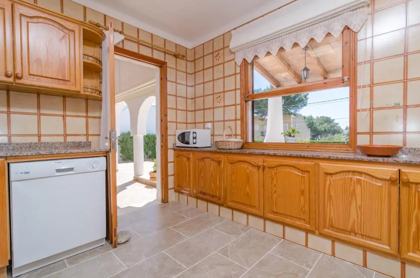 A tiled kitchen with wooden cabinets and a large window.