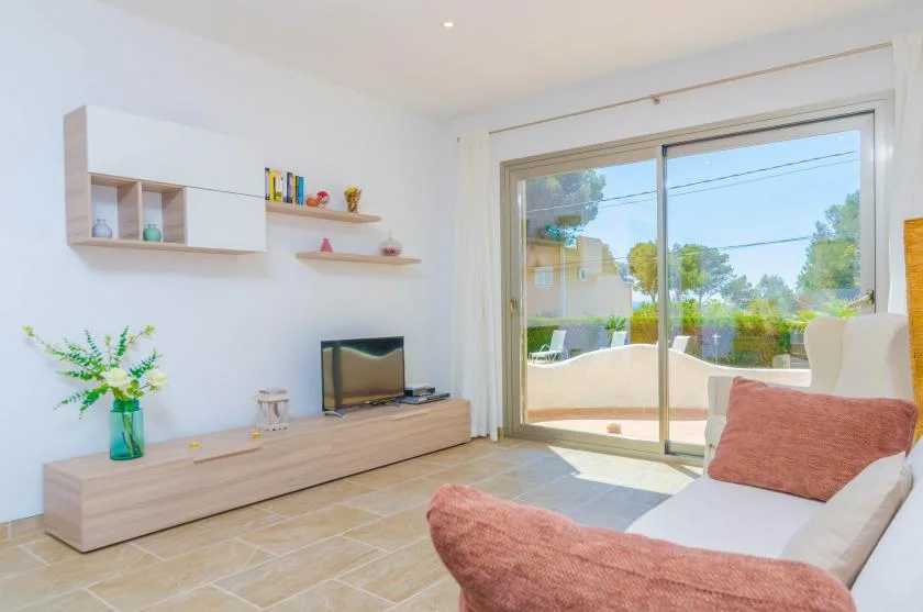 A bright living room with a television and sliding glass doors opening onto a patio.