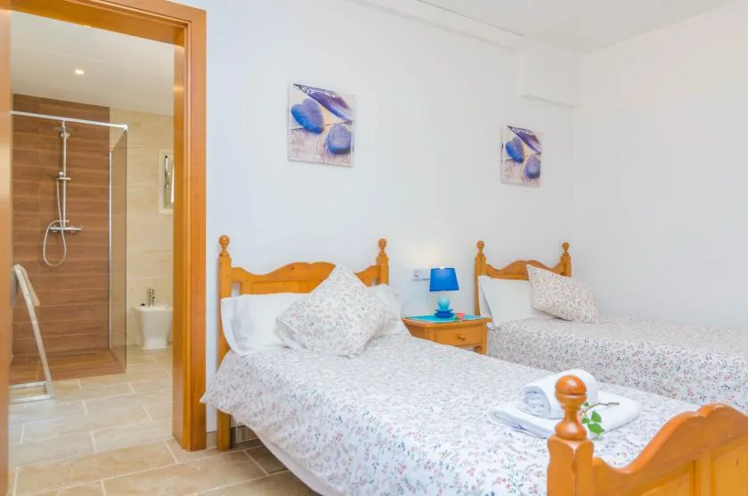 A bedroom with two beds and an open bathroom doorway.