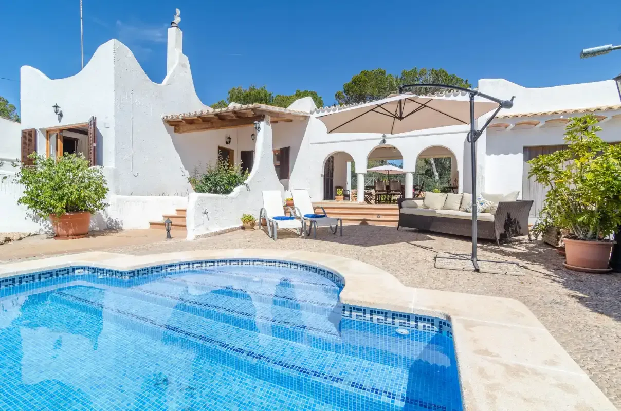 A courtyard pool sits beside white buildings and an outdoor seating area.