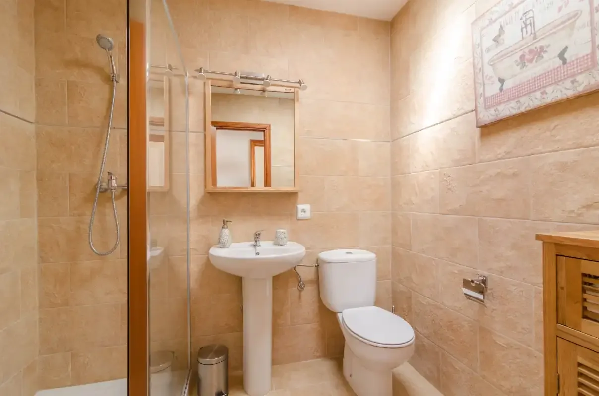 A tiled bathroom with a shower, sink, and toilet.