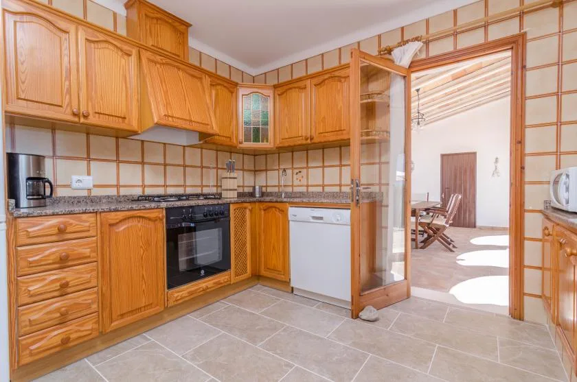 A kitchen with wooden cabinets and a dishwasher beside an open doorway.