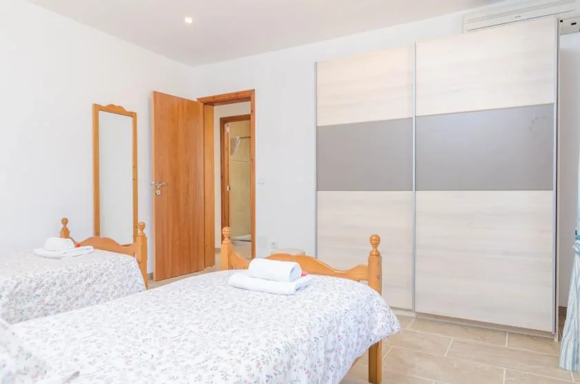 A bedroom with two beds, a wardrobe, and an open wooden door.