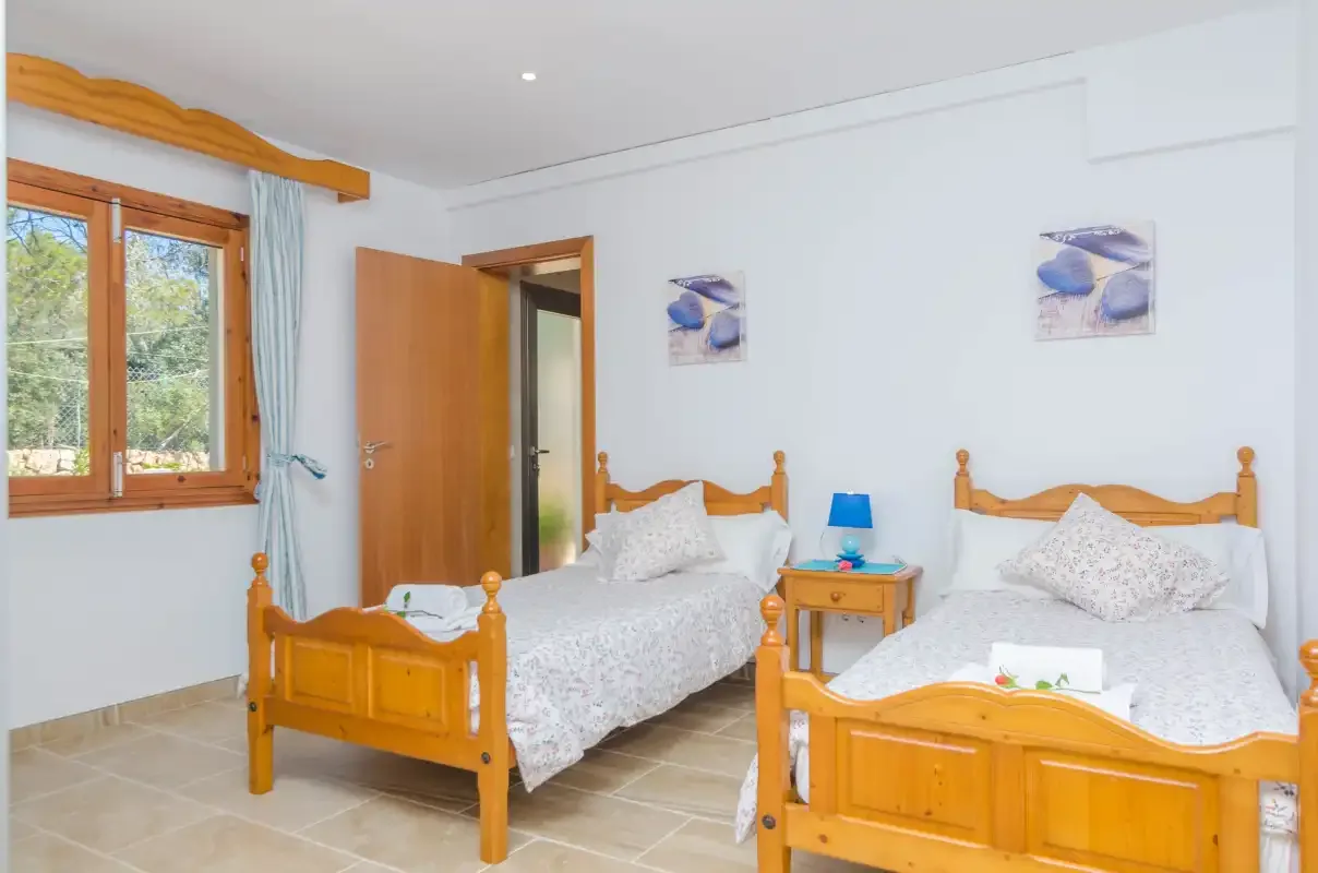 A bright bedroom with two wooden beds and a window.