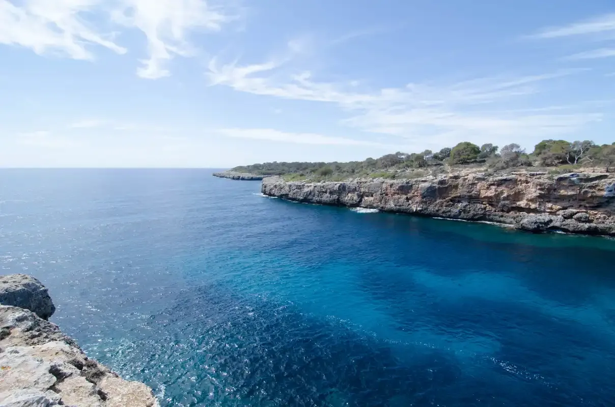 A coastal cove with blue water and rocky cliffs along the shoreline.