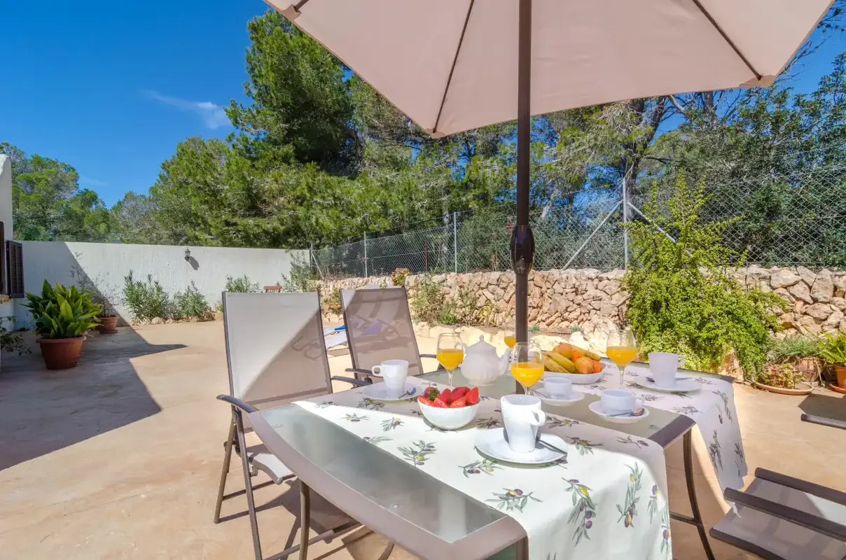 A patio dining area is set with a table beneath a large umbrella.