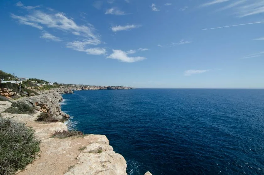 A rocky coastline overlooks the blue sea beneath a clear sky.