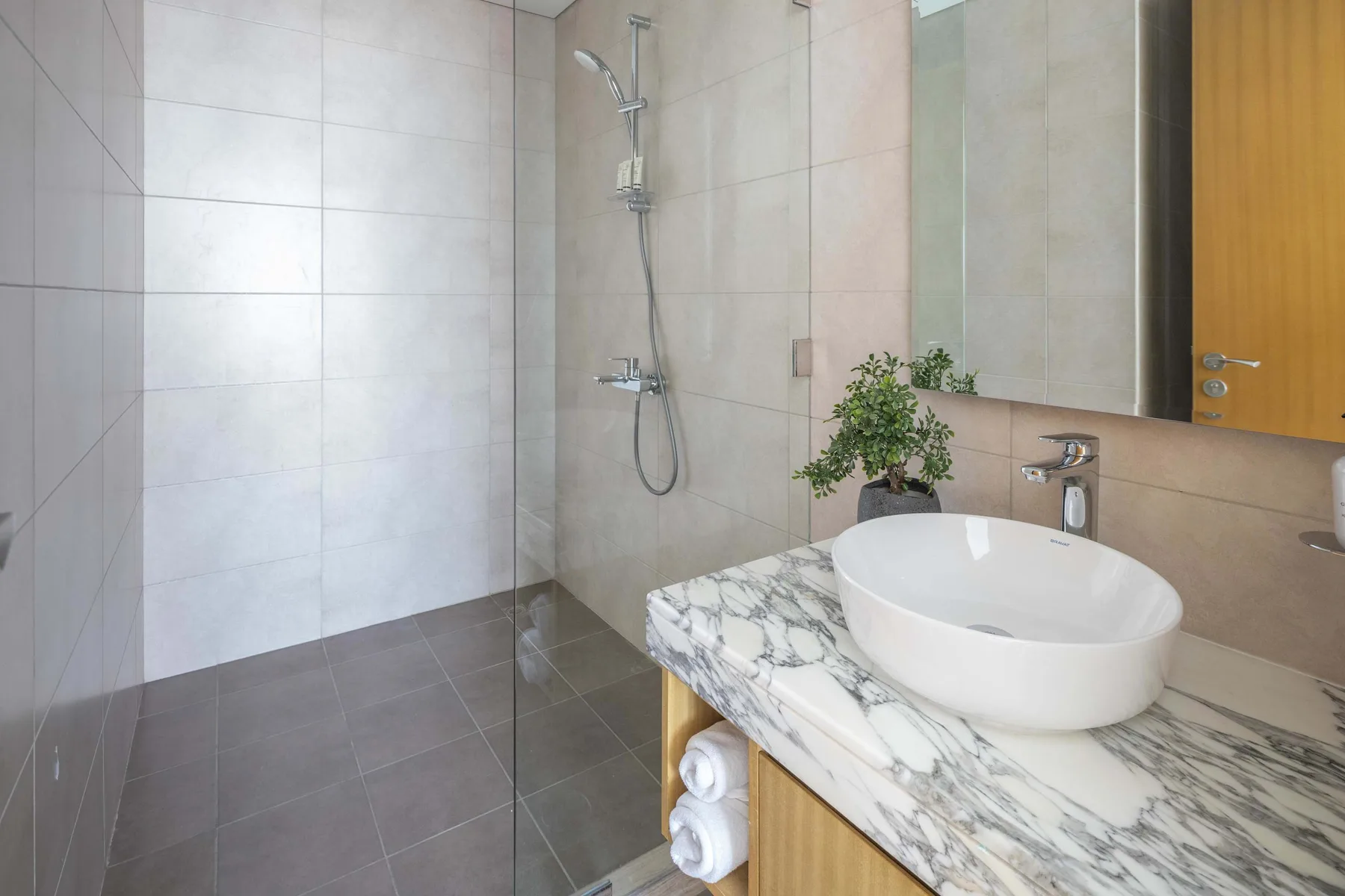 A tiled bathroom with a glass shower and a white vessel sink.
