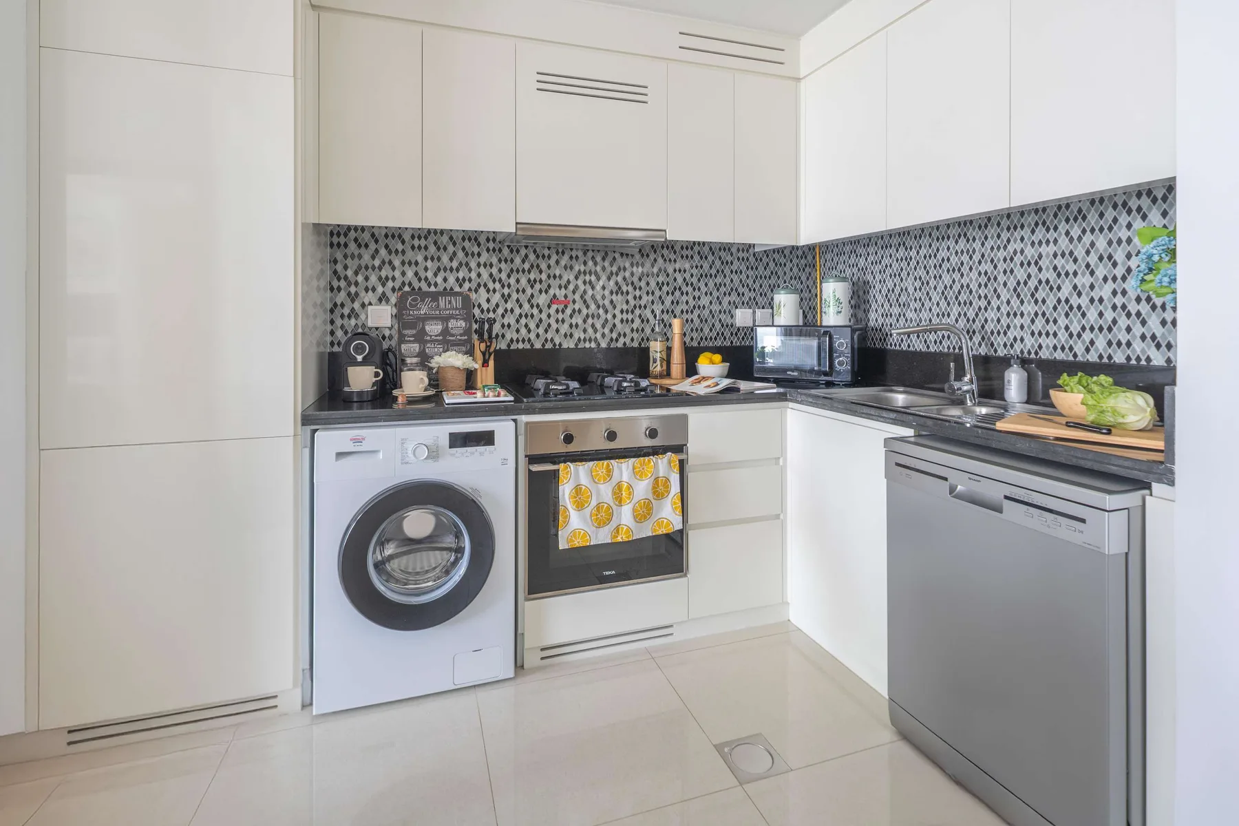 A modern kitchen with white cabinets, a patterned backsplash, and stainless steel appliances.