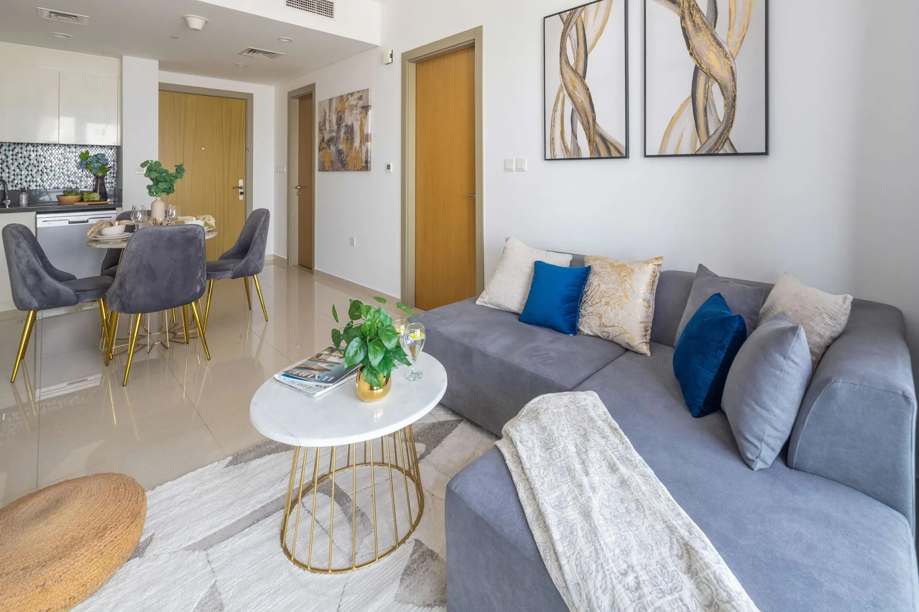 Una sala de estar moderna con un sofá seccional gris y un comedor.