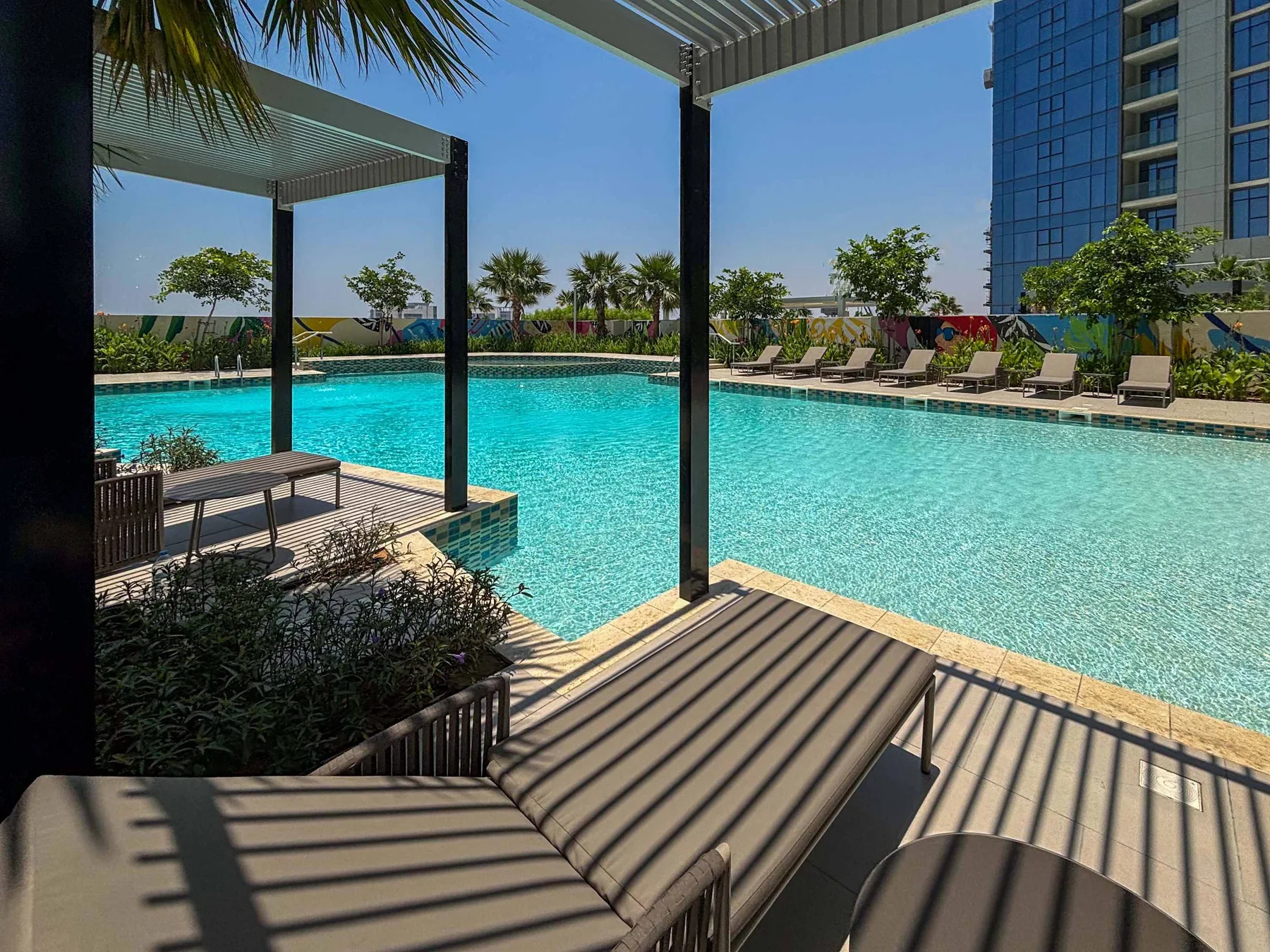 An outdoor swimming pool with lounge chairs and shaded seating areas.
