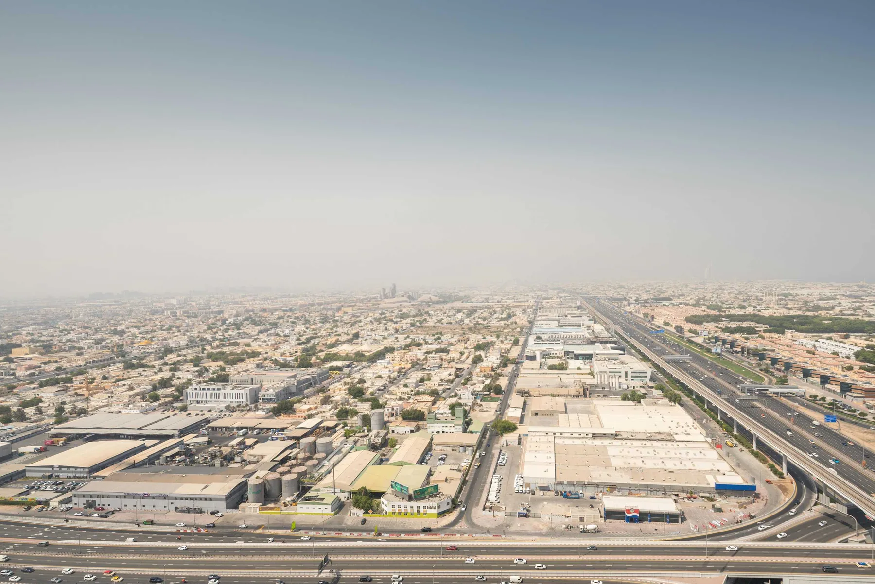 An aerial view of a sprawling urban area with roads and low-rise buildings.