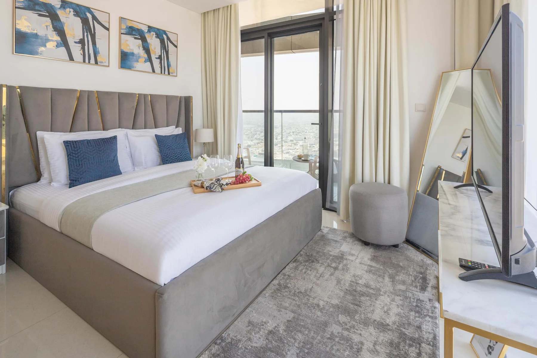 A bedroom with a large bed, framed artwork, and glass doors opening to a balcony.