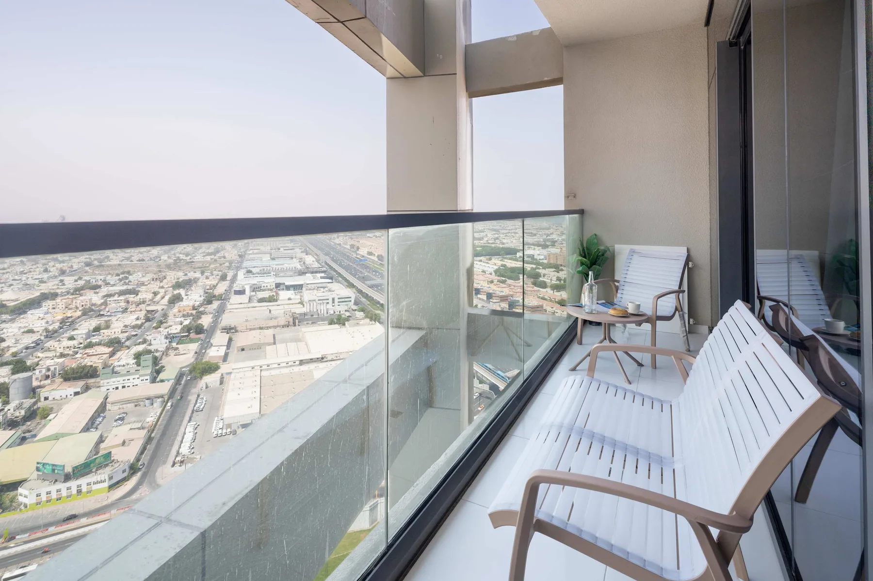 A balcony with seating and a glass railing overlooks the surrounding city.