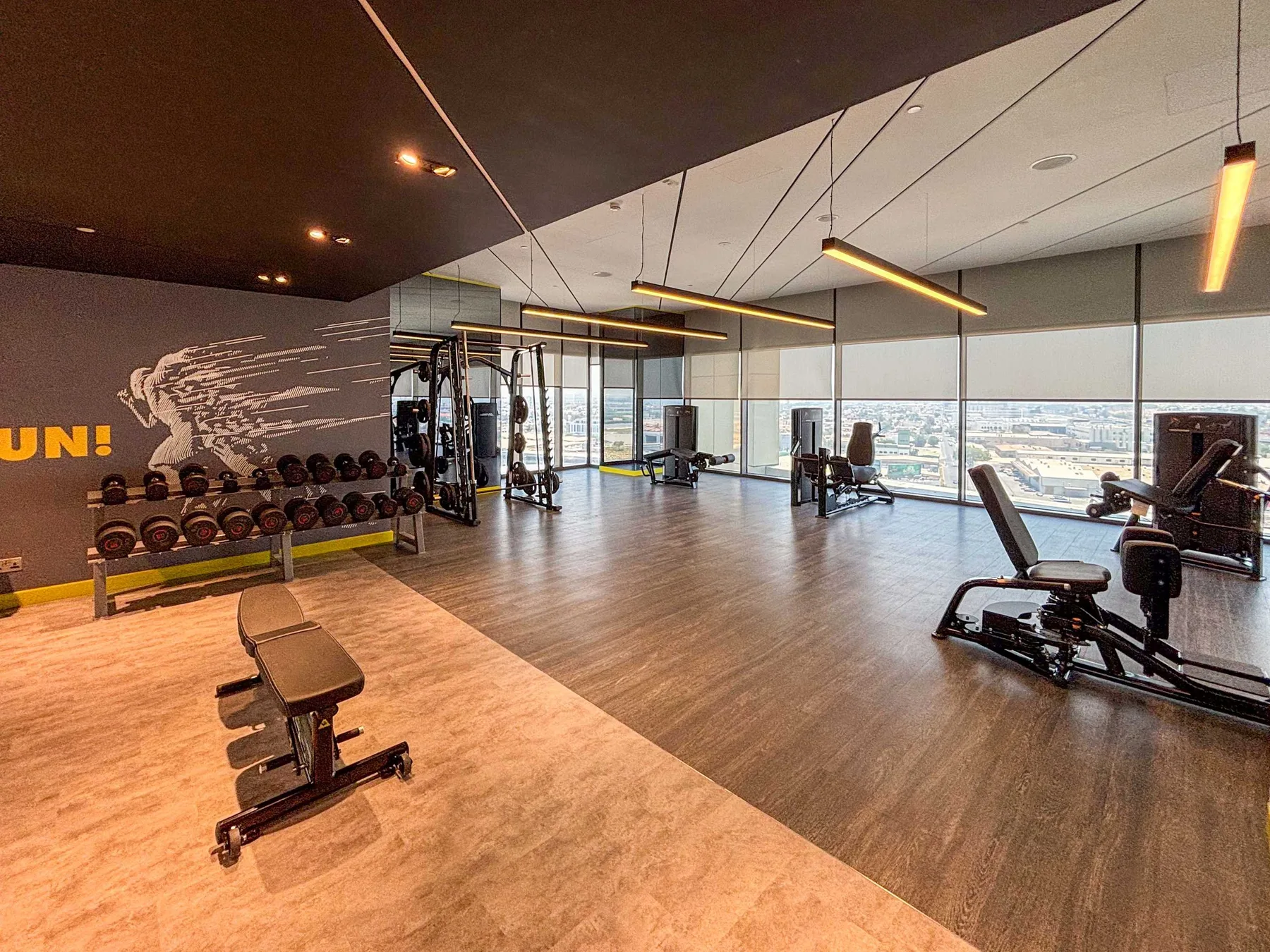 A gym with exercise equipment and large windows overlooking the city.