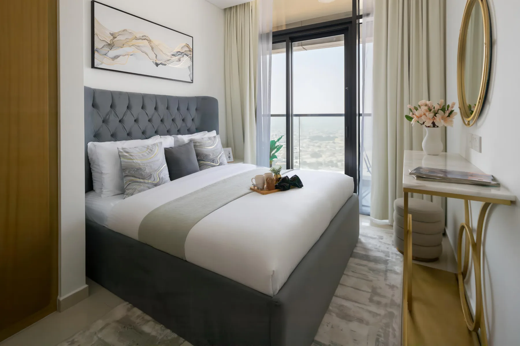 A bedroom with a neatly made bed beside a floor-to-ceiling window.