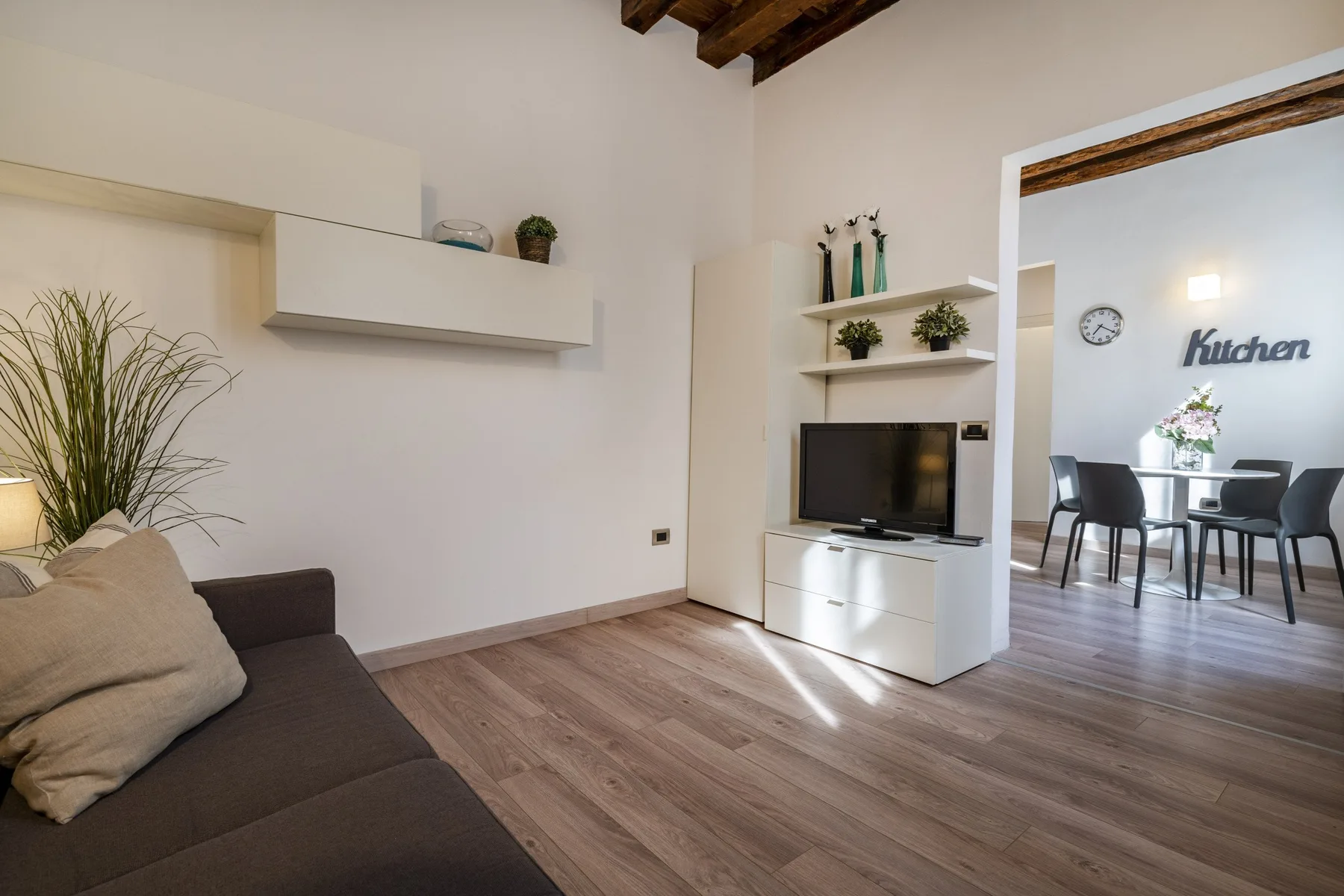 A living room with a television and seating beside an open dining area.