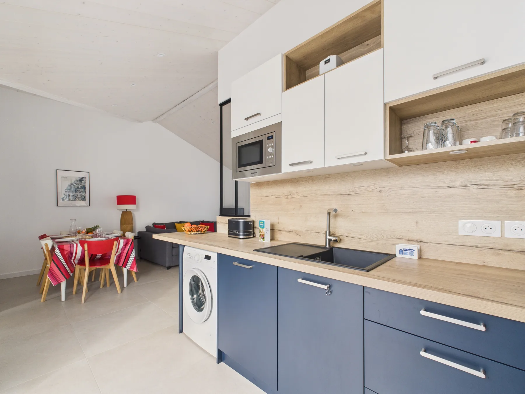 A modern kitchen with blue cabinets and a small dining area.