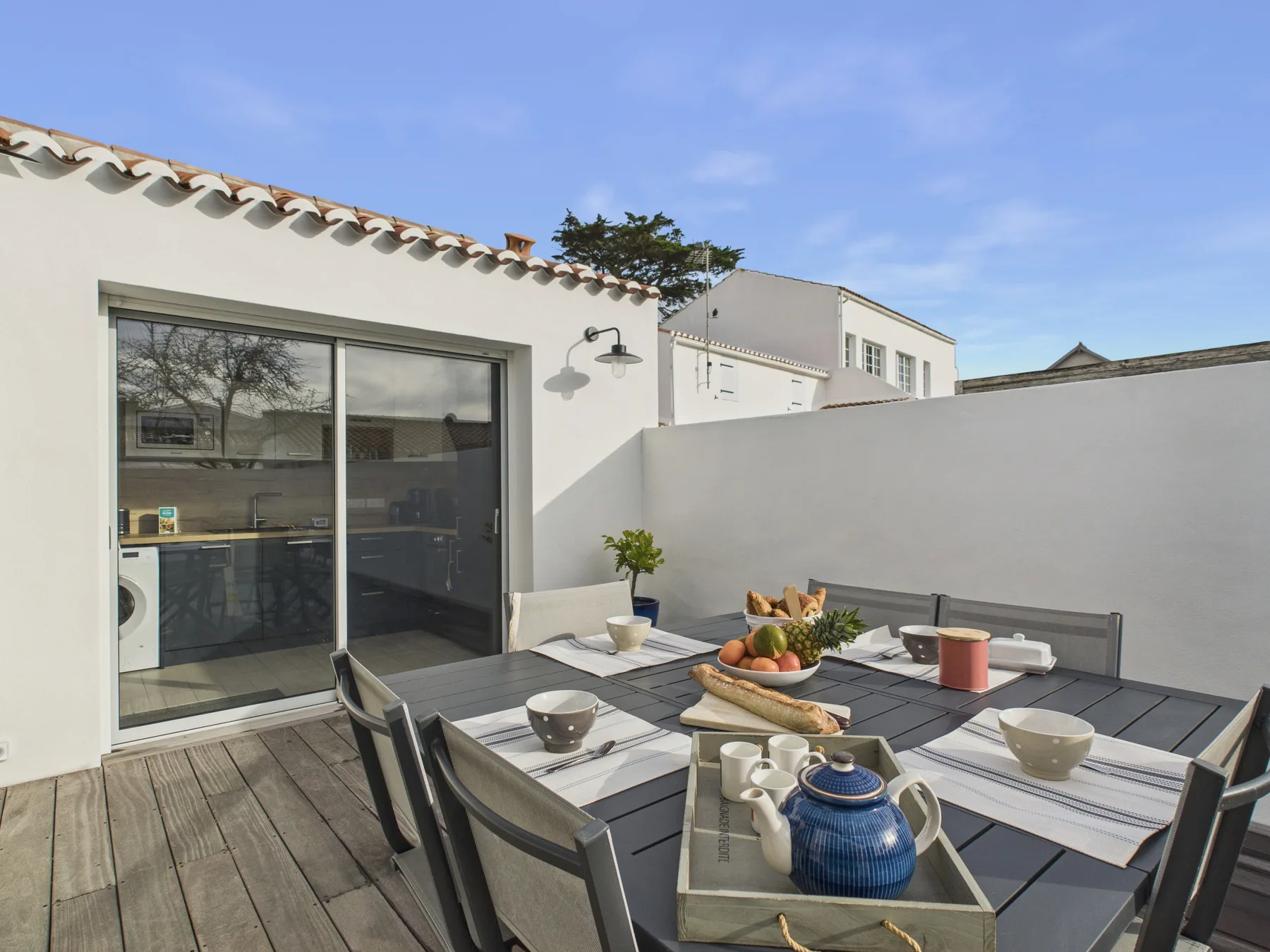 An outdoor dining area on a patio, with a table and seating beside the house.