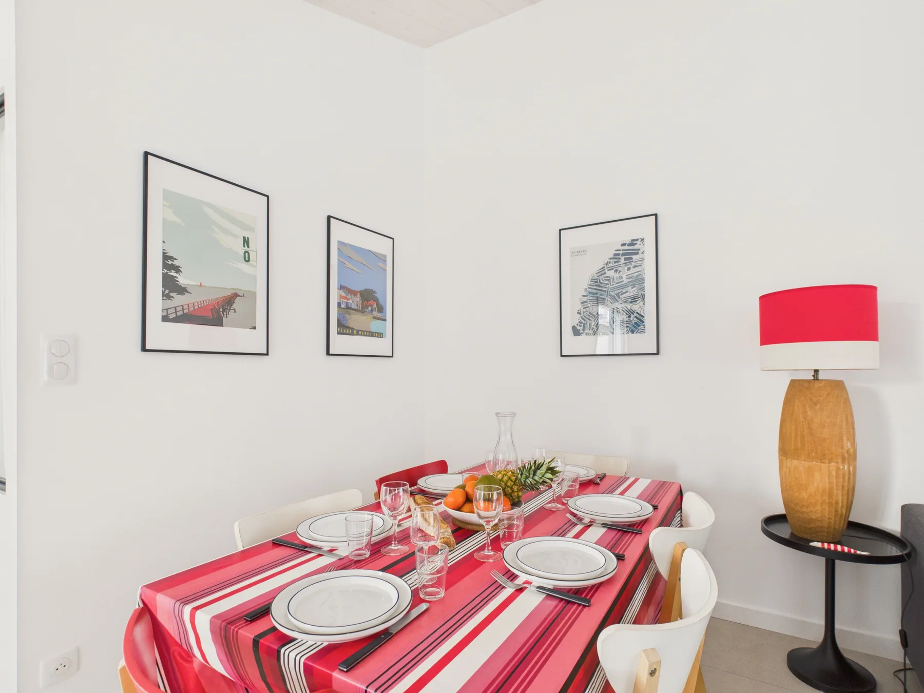 A dining area with a table set with dishes beneath framed wall art.