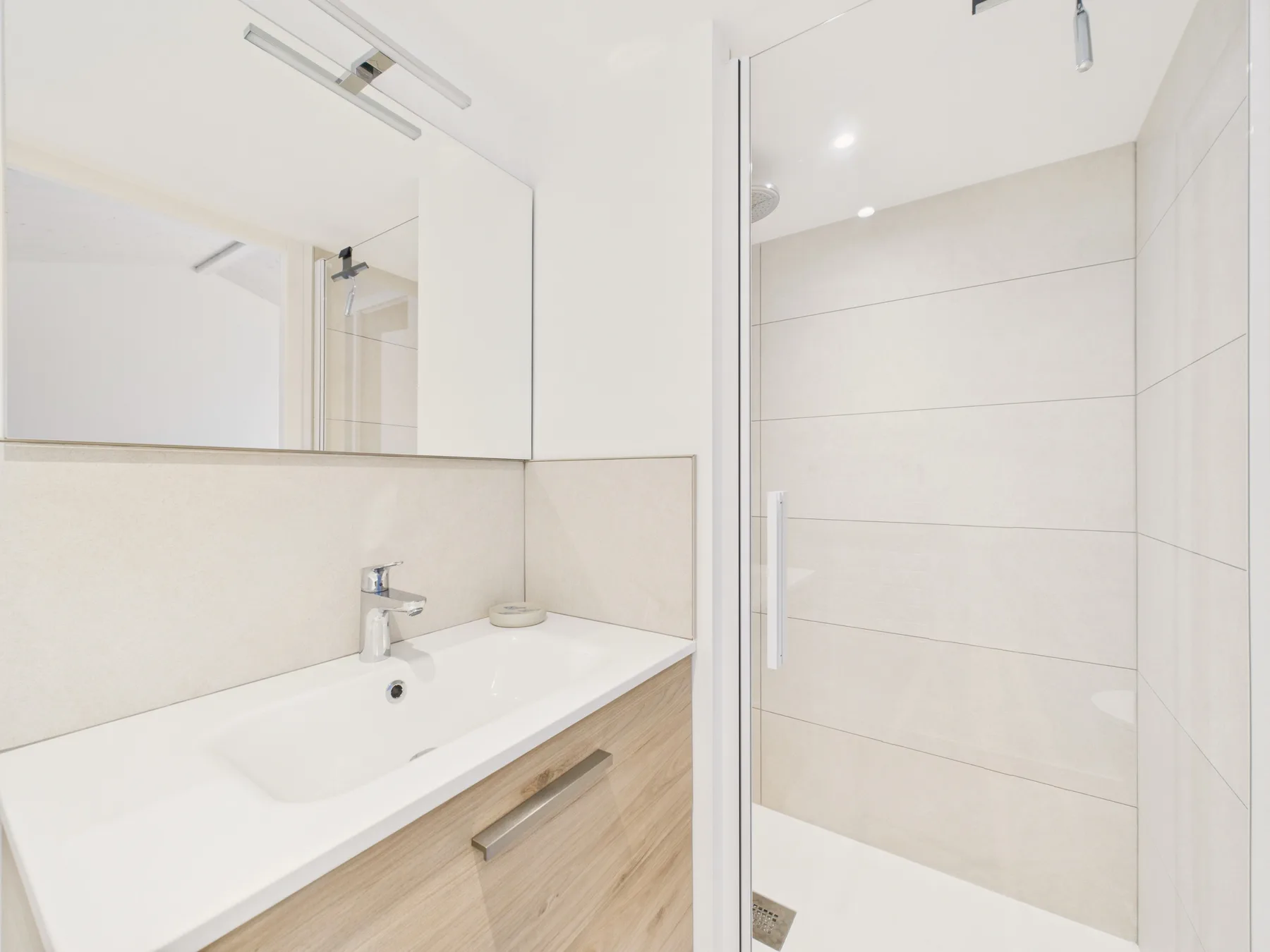 A bright bathroom with a sink and shower.