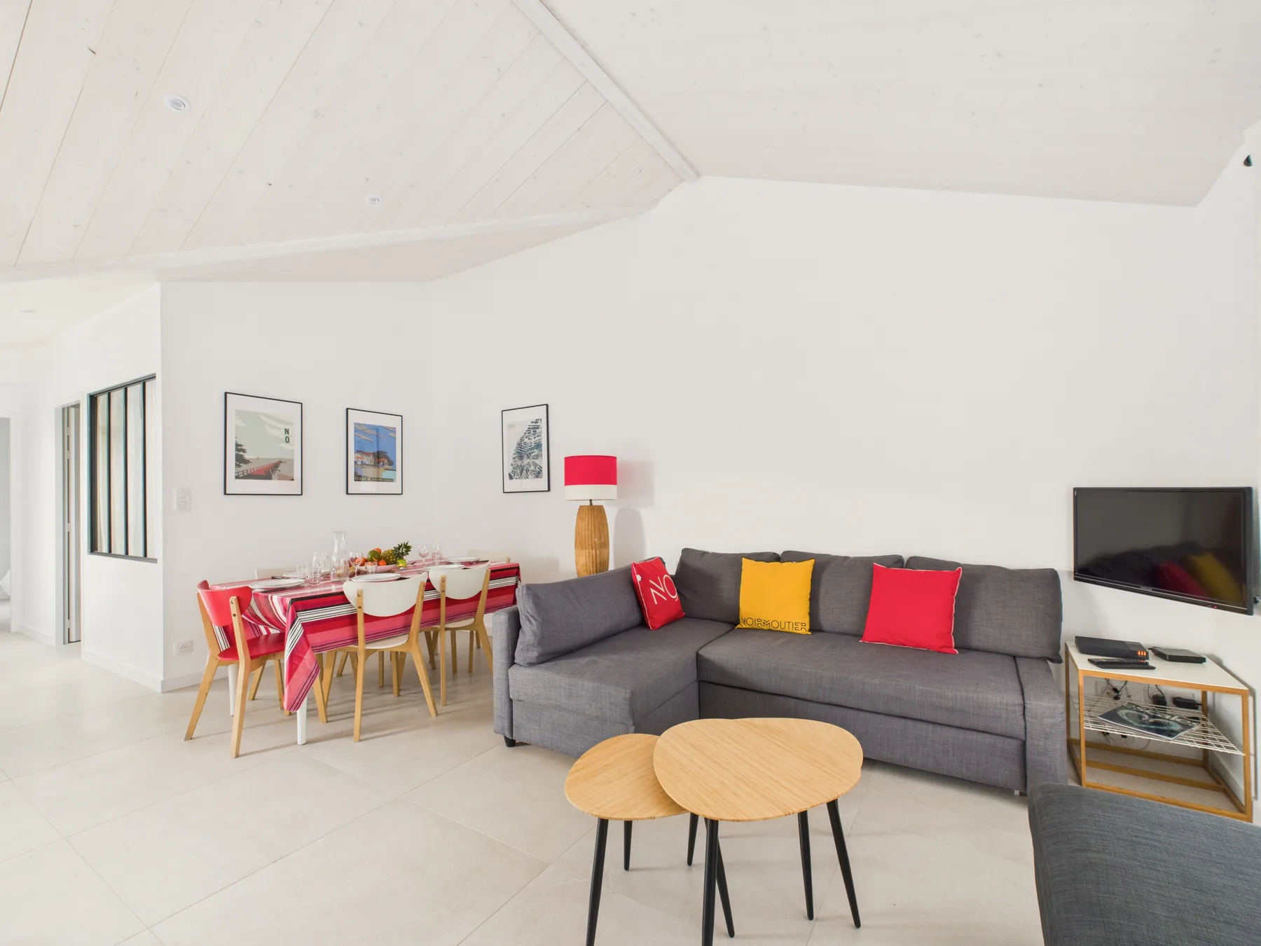 A bright living and dining area with a gray sofa and dining table.