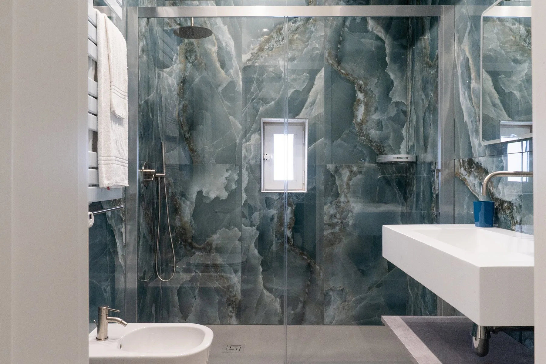 Un baño con una ducha de vidrio y un lavabo blanco grande.