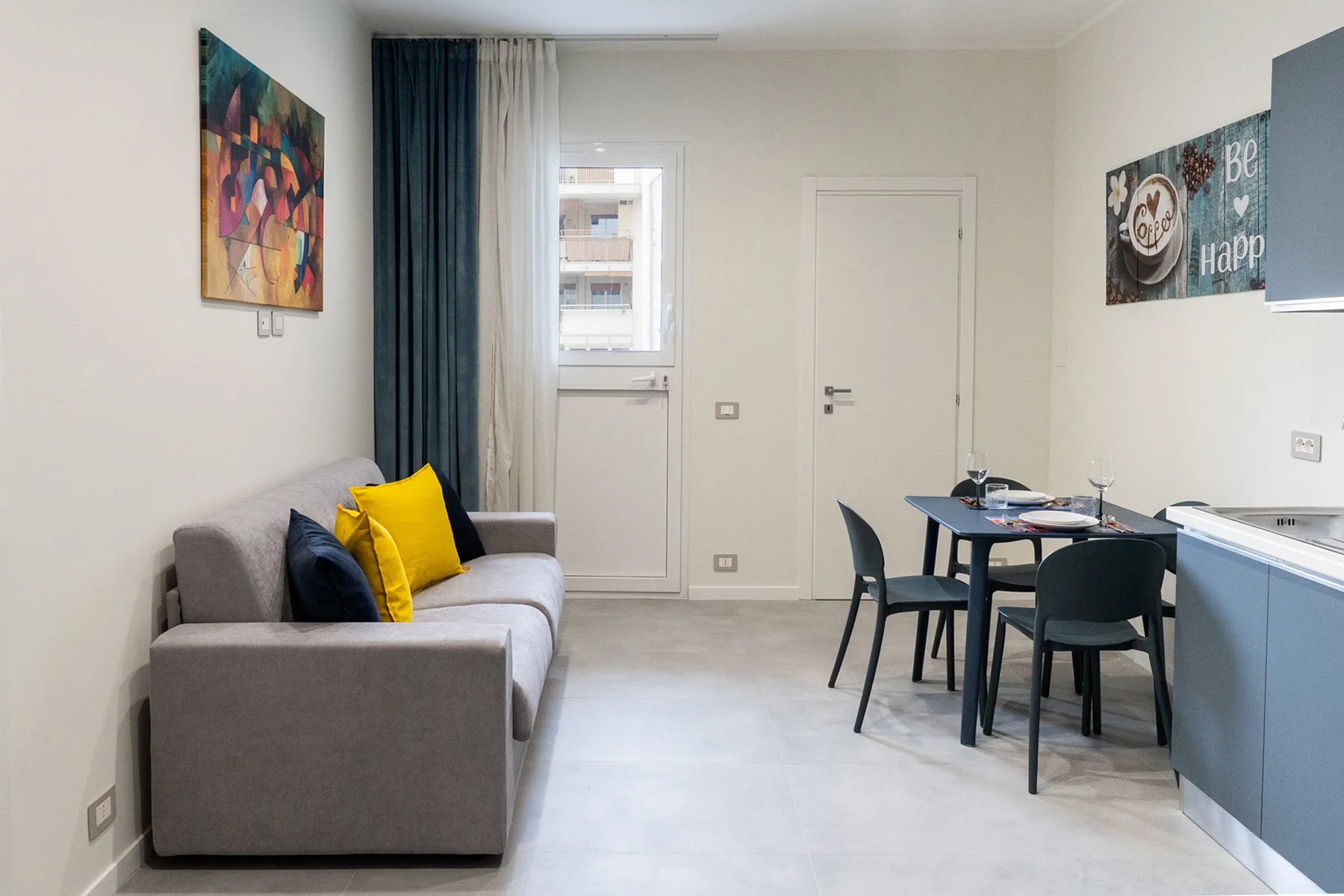 Una zona de estar y comedor con sofá gris, mesa y sillas.